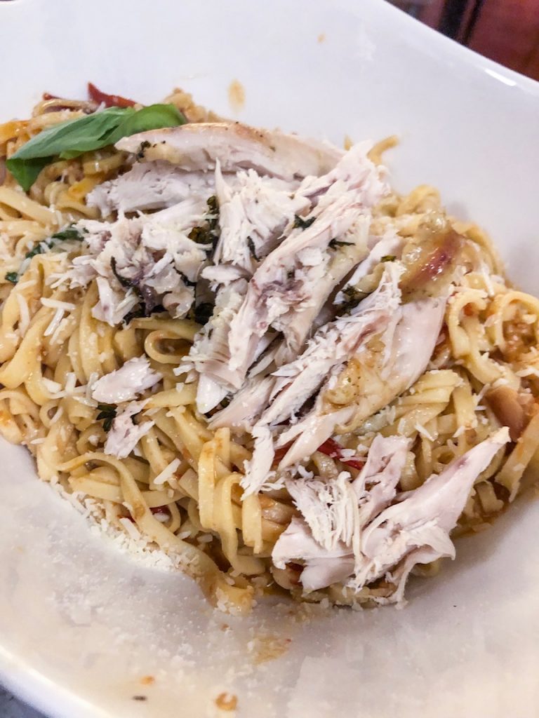 Sliced roast chicken on a bed of fresh pasta